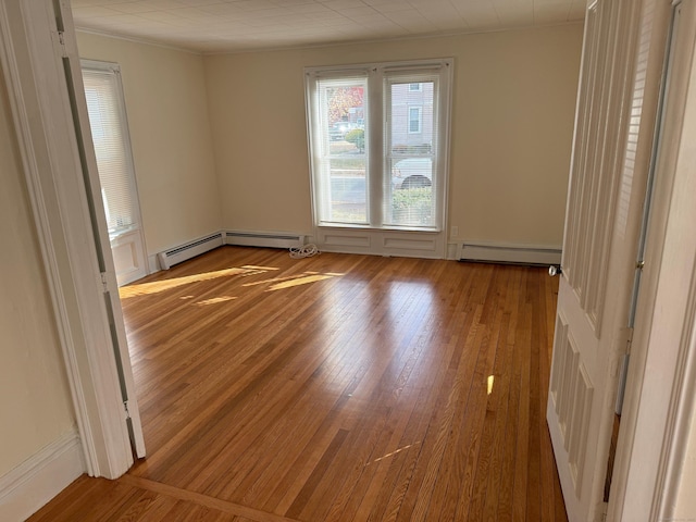 unfurnished room featuring plenty of natural light, wood finished floors, and baseboard heating