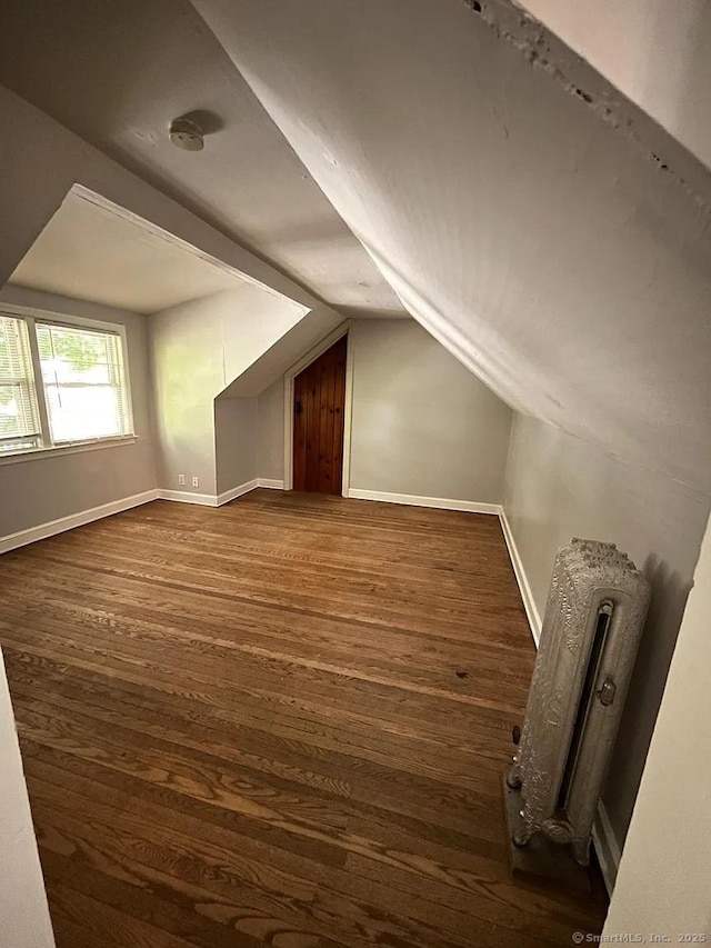 bonus room with baseboards, dark wood-style flooring, and vaulted ceiling