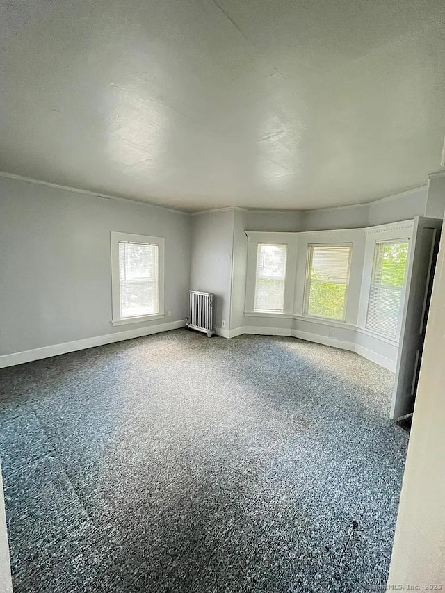 empty room featuring radiator and baseboards