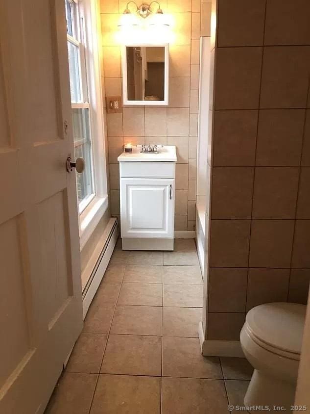 bathroom with tile walls, toilet, tile patterned flooring, and a baseboard heating unit