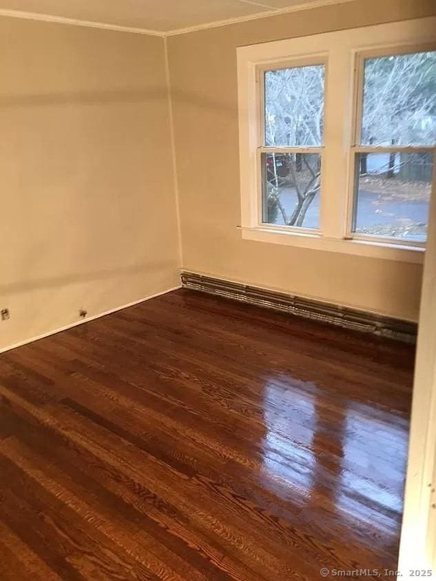 empty room with crown molding and dark wood-style floors