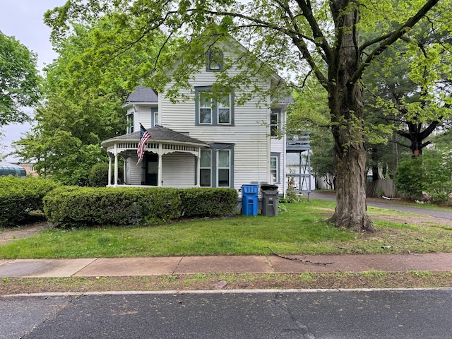 victorian-style house featuring covered porch and a front yard