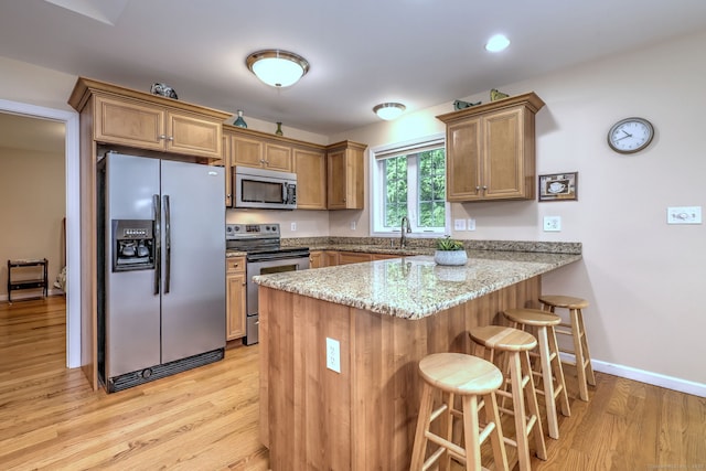 30 Prosperity Ct Unit 25, Southington, CT 06489 - kitchen with appliances with stainless steel finishes, a peninsula, light wood-type flooring, a kitchen bar, and light stone countertops