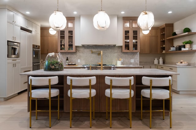 26 Hitchcock Rd, Westport, CT 06880 - kitchen featuring tasteful backsplash, an island with sink, light stone countertops, a kitchen bar, and recessed lighting