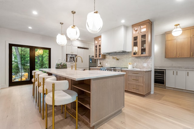 26 Hitchcock Rd, Westport, CT 06880 - kitchen featuring wine cooler, custom range hood, light wood-type flooring, backsplash, and a large island