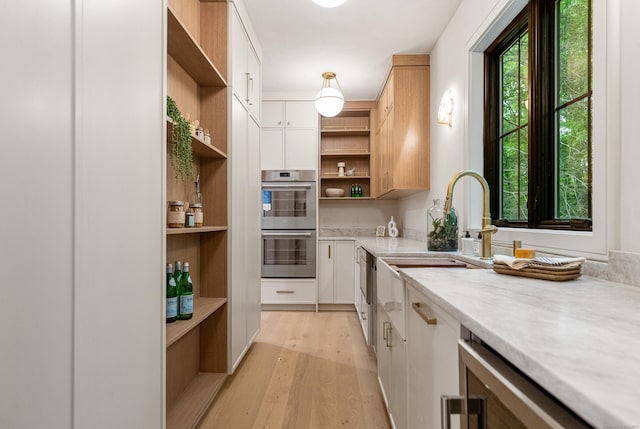 26 Hitchcock Rd, Westport, CT 06880 - kitchen with open shelves, stainless steel double oven, light wood finished floors, beverage cooler, and a sink