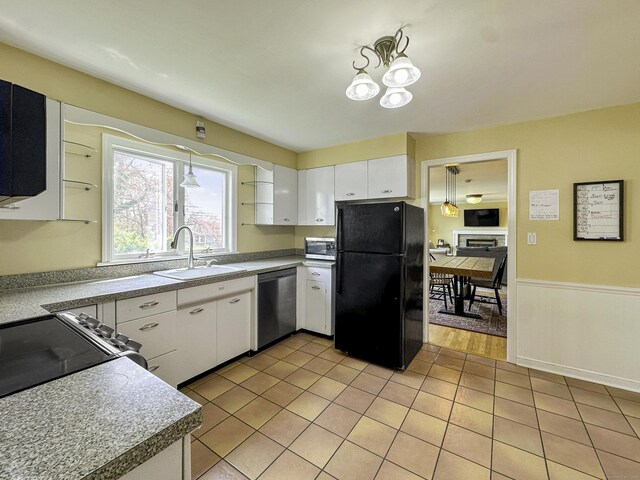 870 Lakeside Dr, Bridgeport, CT 06606 - kitchen with a sink, a wainscoted wall, white cabinets, appliances with stainless steel finishes, and light tile patterned flooring