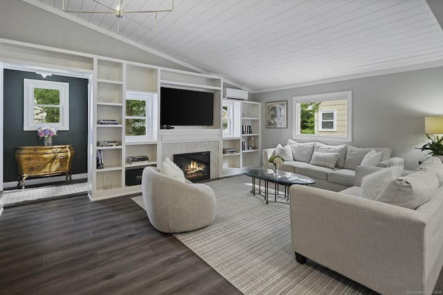 living area featuring vaulted ceiling, a wall mounted air conditioner, dark wood-style flooring, a glass covered fireplace, and built in shelves
