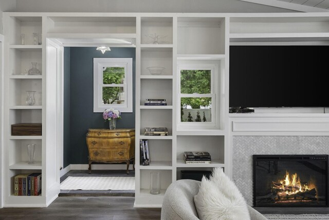 interior space with built in shelves, a tile fireplace, baseboards, and dark wood finished floors