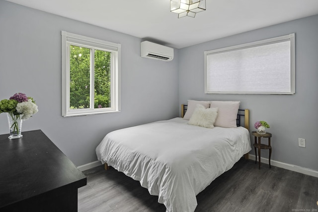 bedroom featuring baseboards, a wall unit AC, and wood finished floors