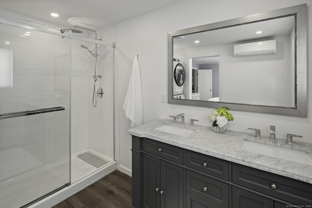 full bath with a wall unit AC, stacked washer / dryer, a stall shower, wood finished floors, and double vanity