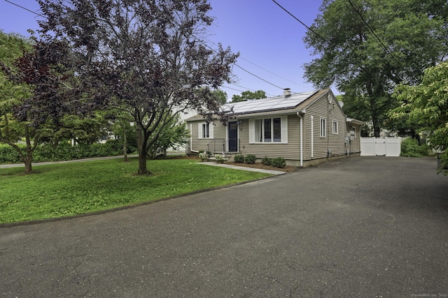 ranch-style house featuring solar panels and asphalt driveway