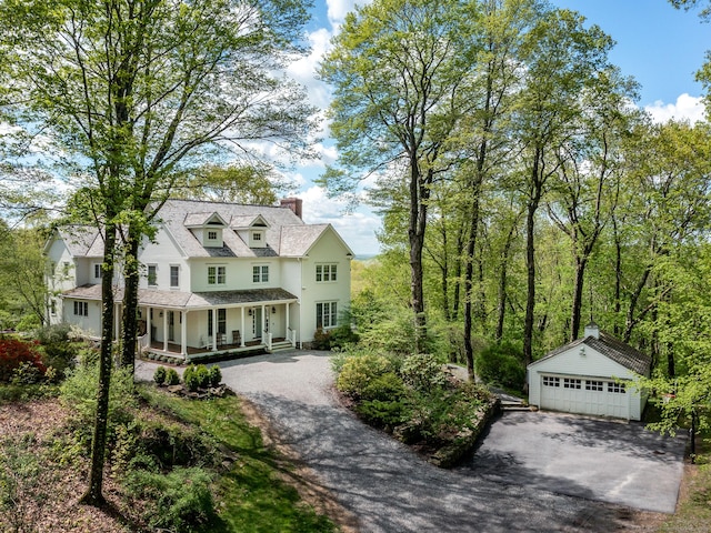 view of front of house featuring covered porch, a chimney, an outdoor structure, a detached garage, and stucco siding