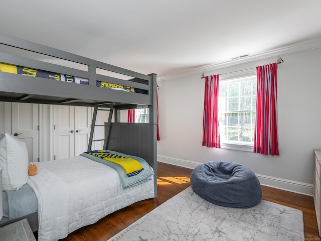 bedroom with baseboards, ornamental molding, and wood finished floors