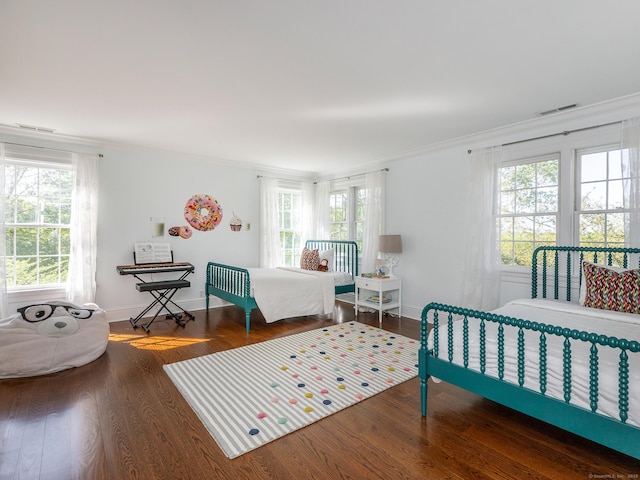 bedroom with crown molding, wood finished floors, and baseboards