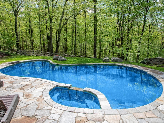 view of pool featuring a pool with connected hot tub, a fenced backyard, and a patio area