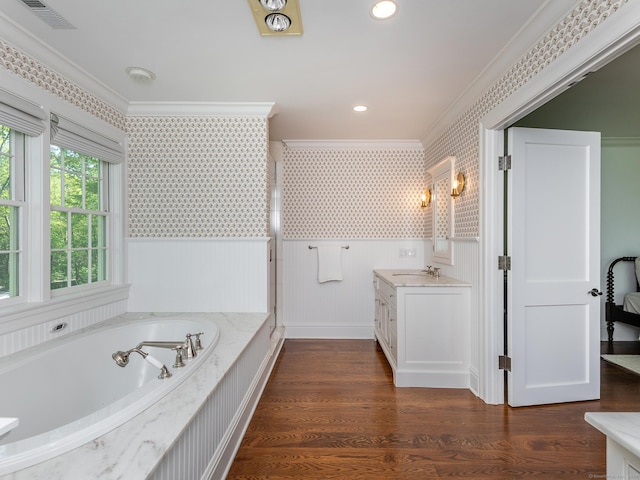 full bath featuring wallpapered walls, ornamental molding, vanity, a garden tub, and a wainscoted wall