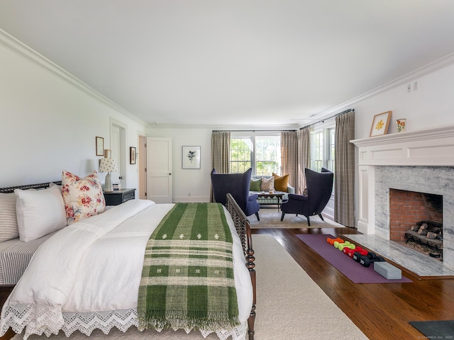 bedroom featuring wood finished floors, crown molding, a high end fireplace, and baseboards