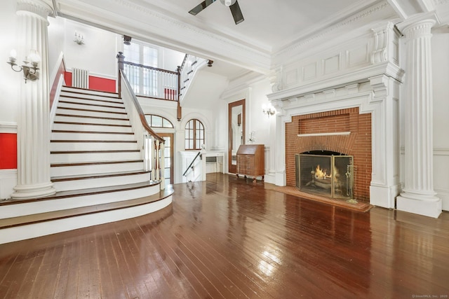 unfurnished living room with hardwood / wood-style flooring, stairs, decorative columns, crown molding, and ceiling fan