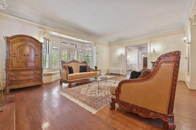 living area with radiator heating unit, crown molding, and hardwood / wood-style flooring