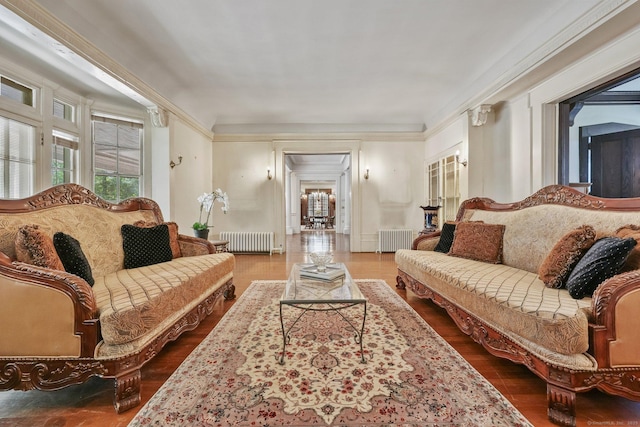 living area with radiator, crown molding, and wood finished floors