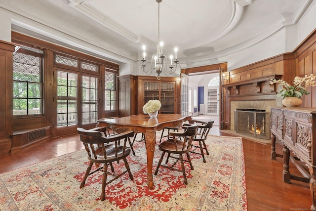 dining space with a notable chandelier, visible vents, hardwood / wood-style flooring, ornamental molding, and a high end fireplace