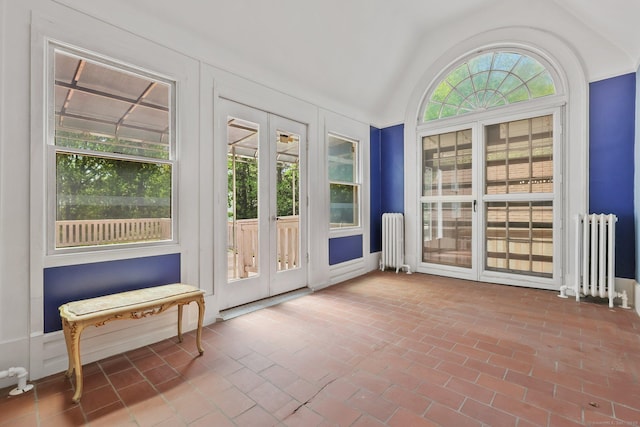 doorway to outside featuring vaulted ceiling, brick floor, and radiator heating unit