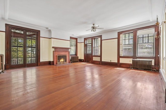 unfurnished living room with radiator, a healthy amount of sunlight, and light wood-type flooring