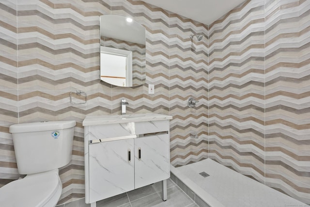 bathroom featuring tile patterned floors, vanity, toilet, and a tile shower