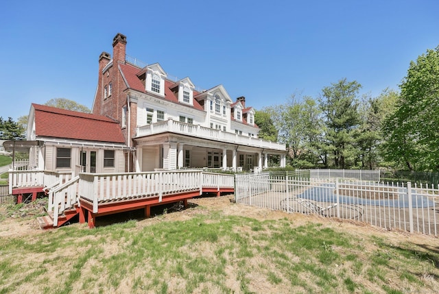 rear view of house with fence, a chimney, and a deck