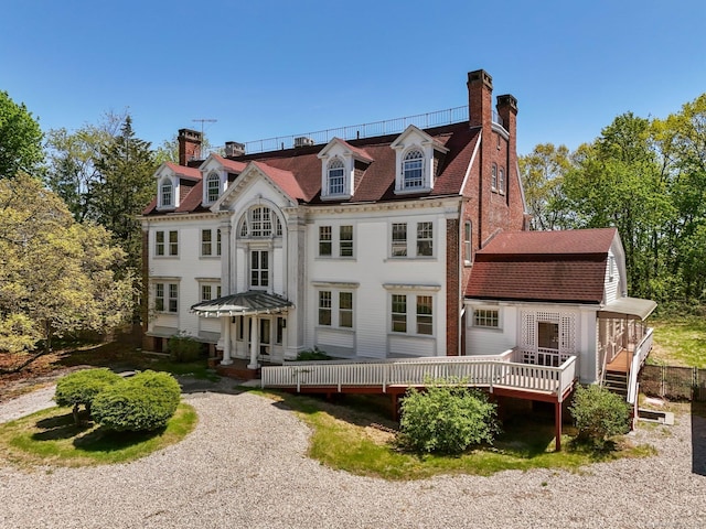 rear view of property featuring a chimney and a deck