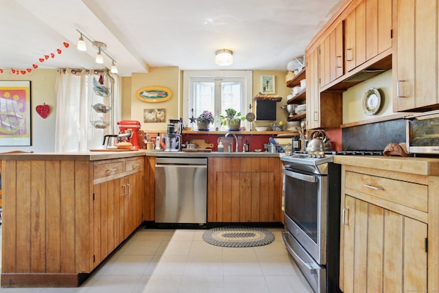 kitchen featuring a sink, a peninsula, light tile patterned flooring, open shelves, and appliances with stainless steel finishes