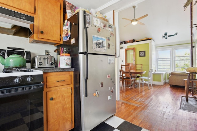 kitchen featuring freestanding refrigerator, black range with gas stovetop, under cabinet range hood, a ceiling fan, and light wood-style floors