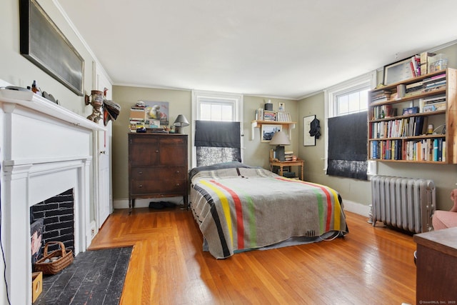 bedroom featuring crown molding, baseboards, a fireplace with flush hearth, and radiator heating unit