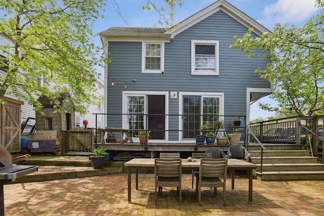 rear view of property featuring a patio area, outdoor dining area, fence, and a deck