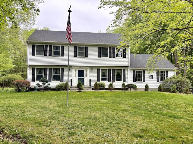 colonial home featuring a front lawn, entry steps, and a shingled roof