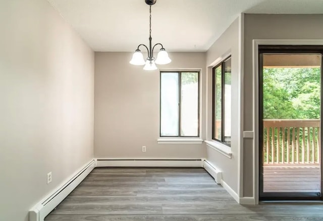 unfurnished dining area with an inviting chandelier, baseboards, baseboard heating, and wood finished floors
