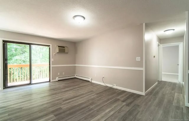 empty room with a textured ceiling, dark wood-style flooring, an AC wall unit, baseboard heating, and baseboards