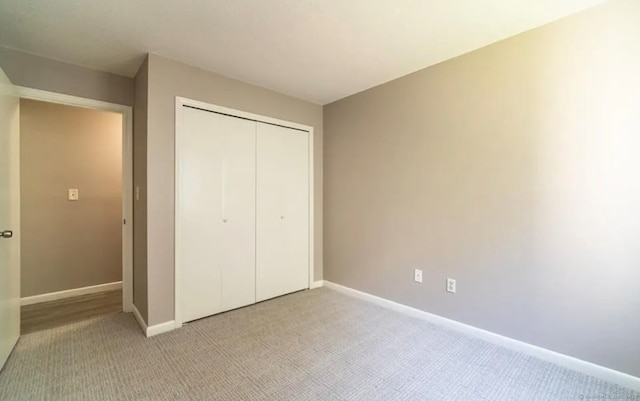 unfurnished bedroom with light carpet, baseboards, and a closet