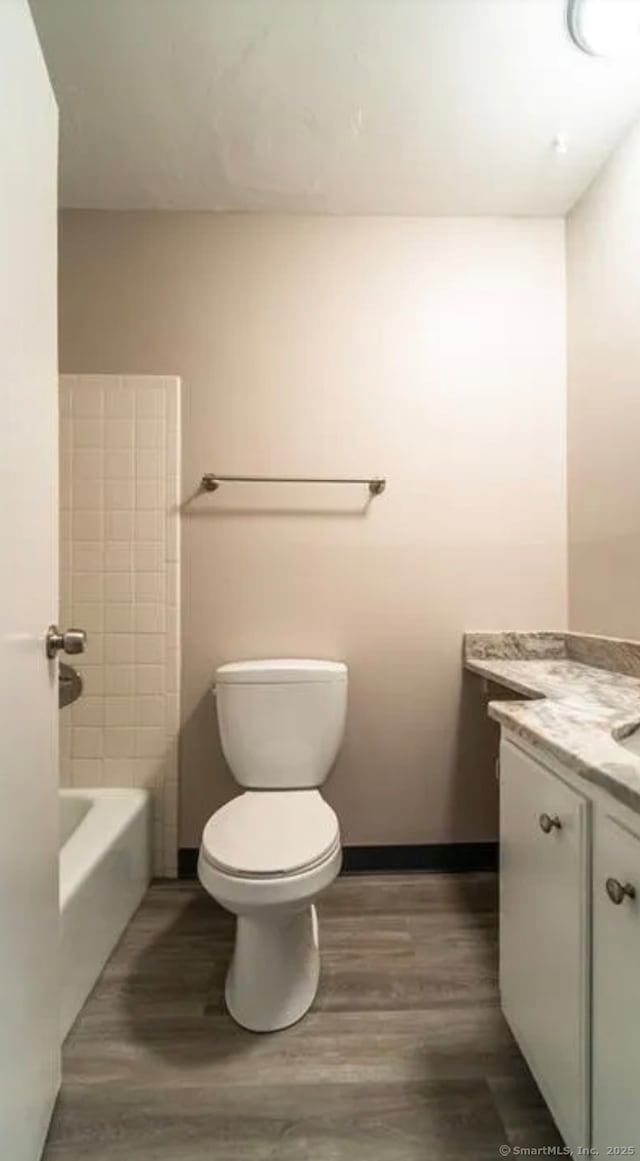 full bath featuring walk in shower, toilet, wood finished floors, vanity, and a washtub
