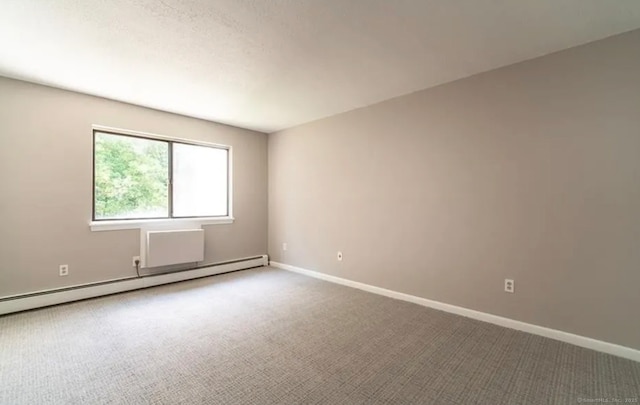 unfurnished room featuring a baseboard heating unit, baseboards, and carpet