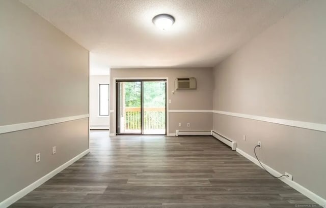 spare room with a textured ceiling, dark wood-style floors, baseboard heating, and a wall mounted AC