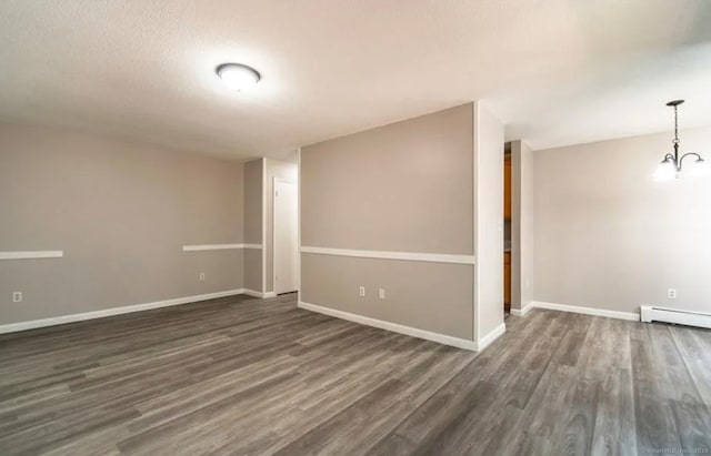 spare room with baseboards, dark wood finished floors, and a baseboard heating unit