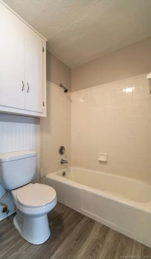 full bathroom with toilet, shower / tub combination, a textured ceiling, and wood finished floors