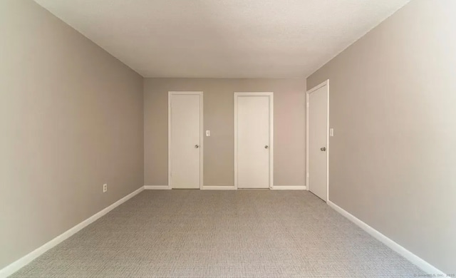 spare room with light carpet and baseboards