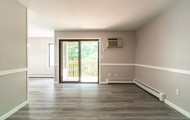 spare room featuring a wall mounted air conditioner, baseboard heating, and wood finished floors