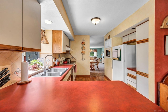 kitchen featuring a sink, range with electric cooktop, under cabinet range hood, freestanding refrigerator, and dark wood finished floors