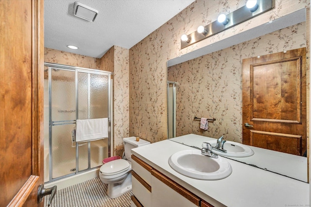 bathroom with a textured ceiling, wallpapered walls, vanity, a stall shower, and tile patterned flooring