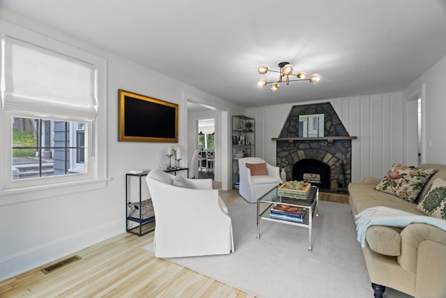 227 Sugar St, Newtown, CT 06470 - living room with wood finished floors, a stone fireplace, baseboards, and a chandelier