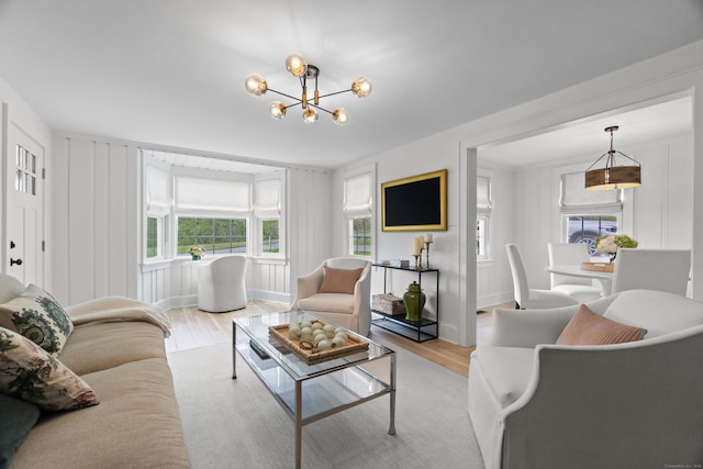 227 Sugar St, Newtown, CT 06470 - living area featuring light wood finished floors, a decorative wall, and a chandelier